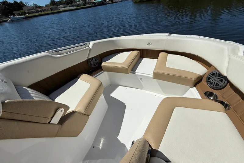 Slide: The Image of 2018 Cobalt 23SC boat interior with tan and white seating, on a calm lake. - 15