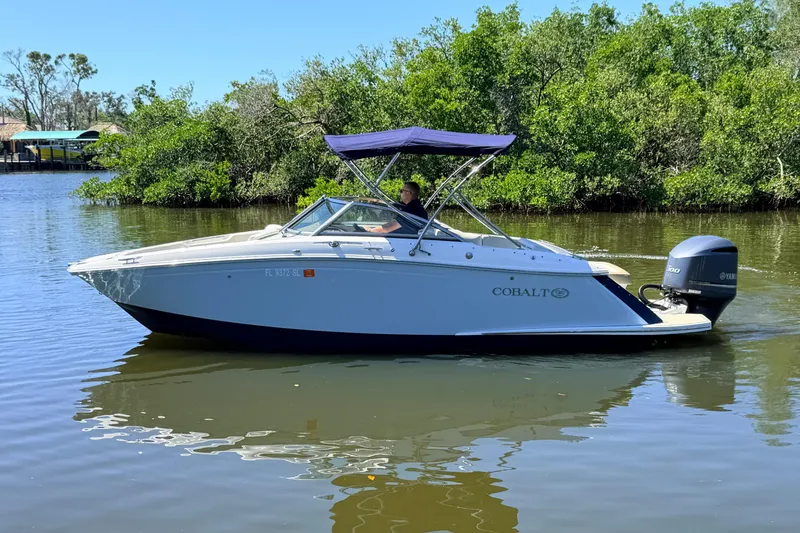 Slide: The Image of 2018 Cobalt 23SC boat cruising on a calm river with lush greenery. - 3