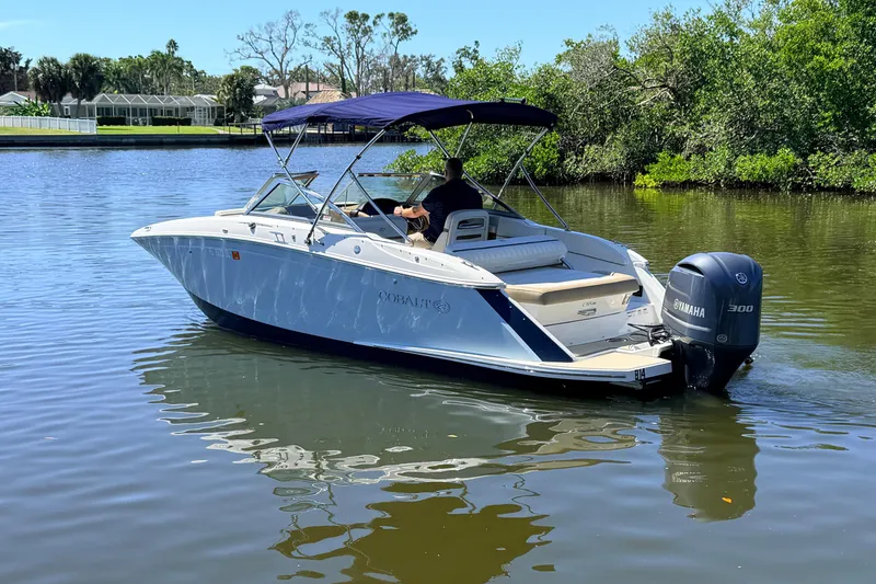 Slide: The Image of 2018 Cobalt 23SC boat cruising on a calm river with lush greenery. - 4
