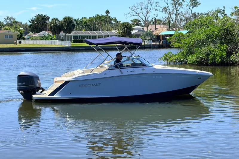 Slide: The Image of 2018 Cobalt 23SC boat cruising on a calm river with lush greenery. - 6