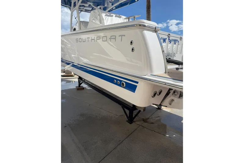 Slide: The Image of 2024 Southport 30 FE boat, white with blue accents, docked under clear sky. - 2