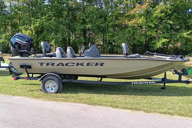 Slide: The Image of 2026 Tracker Pro Team 175 boat on trailer, parked on grass with trees in background. - 3
