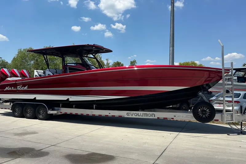 Slide: The Image of 2025 Nor-Tech 390 Sport boat on trailer, red and white design, sunny day. - 13