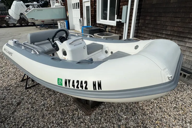 Slide: The Image of 2024 Williams Jet Tenders Sportjet 345 boat displayed on gravel surface. - 2