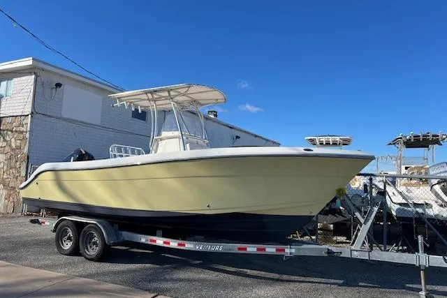 The Image of 2020 Cobia 237 Center Console boat on trailer, parked outdoors under clear blue sky. - 1