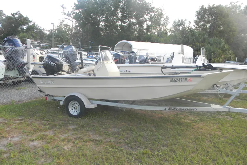 The Image of 2023 SeaArk 1660 c/c boat on trailer, parked outdoors with other boats. - 0