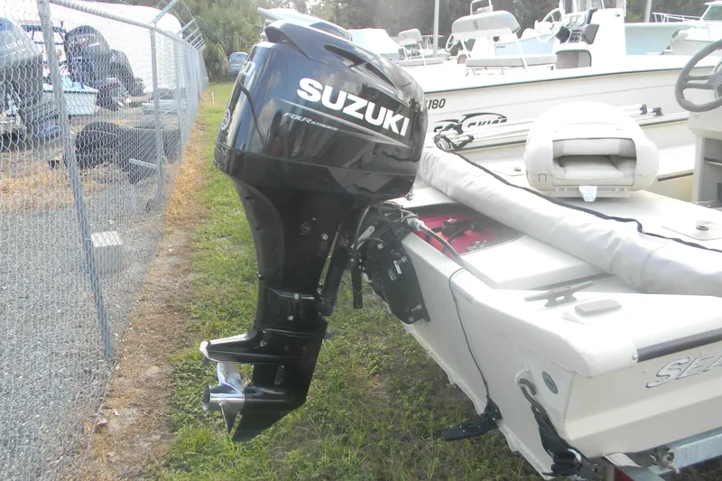 Slide: The Image of 2023 SeaArk 1660 c/c boat with Suzuki outboard motor, parked near a fence. - 9