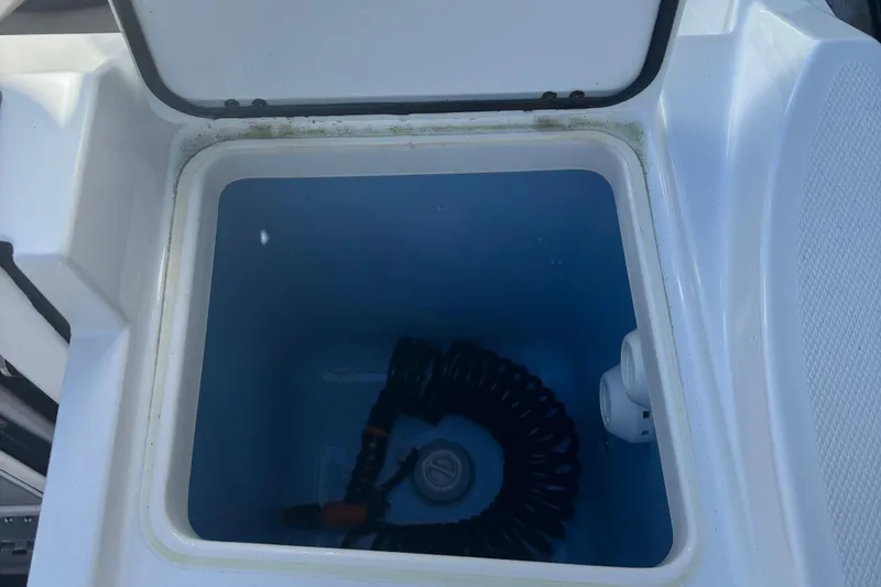 Slide: The Image of Open storage compartment on 2022 Blackfin 252 CC boat with coiled hose inside. - 10