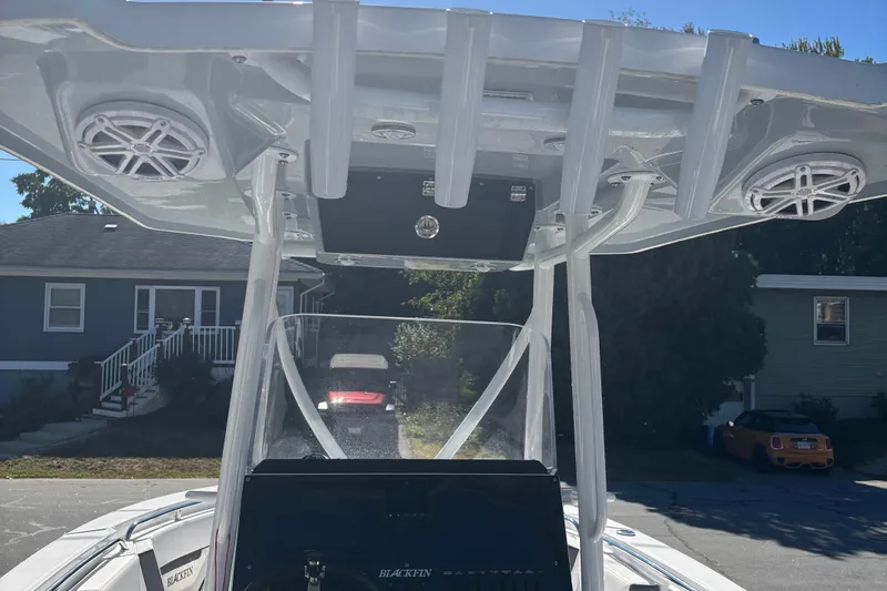 Slide: The Image of 2022 Blackfin 252 CC boat with T-top speakers and console, parked in residential area. - 6