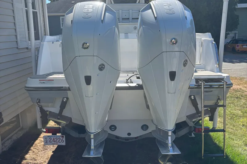 Slide: The Image of 2022 Blackfin 252 CC boat with dual outboard engines, parked near a house. - 7