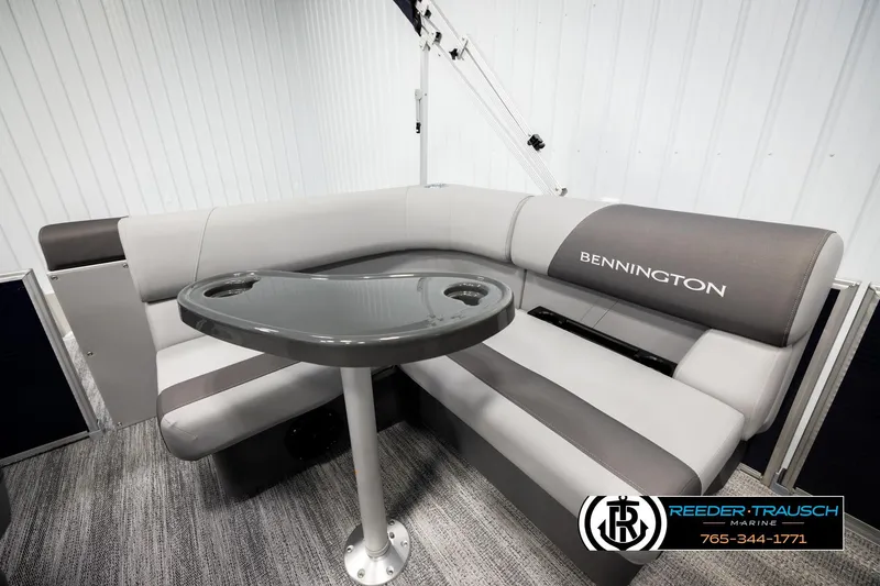 Slide: The Image of 2026 Bennington 188 SLJSE boat interior with gray seating and table, Reeder-Trausch Marine logo. - 23