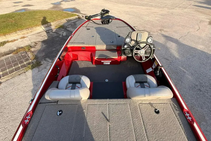 Slide: The Image of 2018 Nitro Z17 boat interior with steering wheel and seating, parked on pavement. - 4