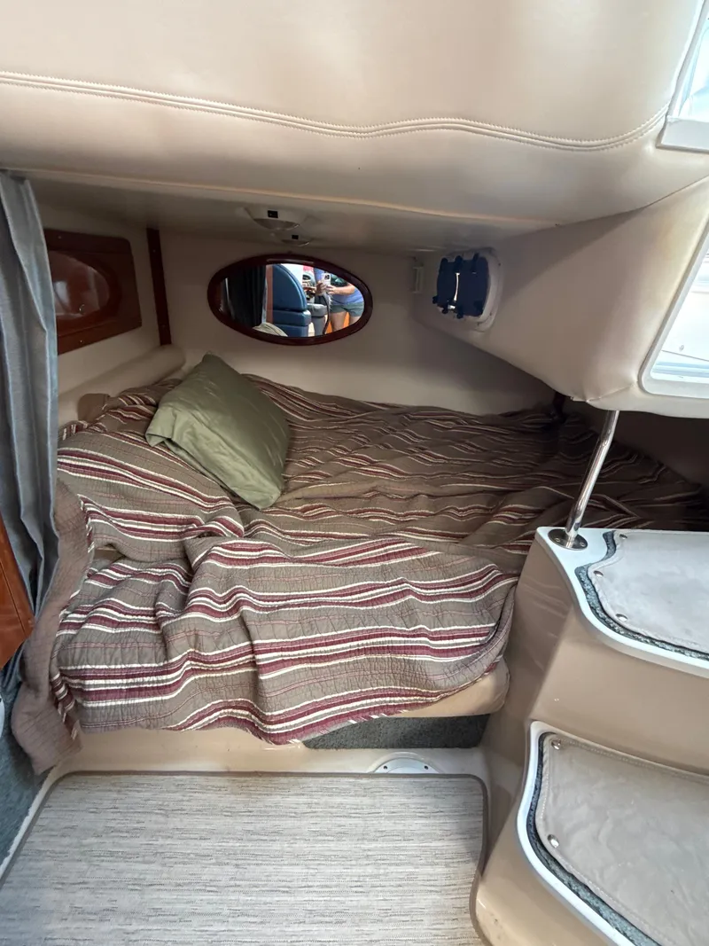 The Image of Cozy cabin interior of 2004 Four 328 Vista boat with striped bedding and porthole window. - 0