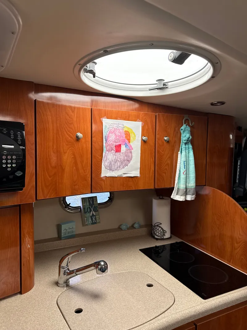 Slide: The Image of Interior of a 2004 Four 328 Vista boat kitchen with wooden cabinets and a circular skylight. - 2