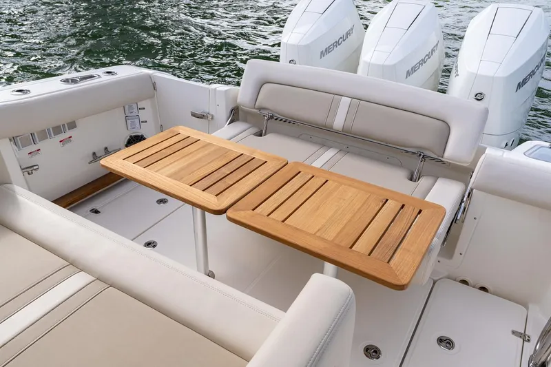 Slide: The Image of Manufacturer Provided Image: 2026 Boston Whaler 350 Realm boat interior with wooden table and Mercury engines. - 8