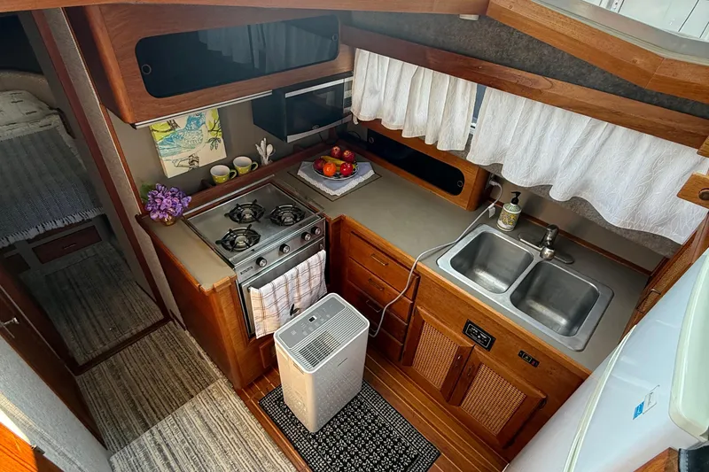 Slide: The Image of 1983 Bayliner 3870 Motoryacht kitchen with stove, sink, and wooden cabinetry. - 14