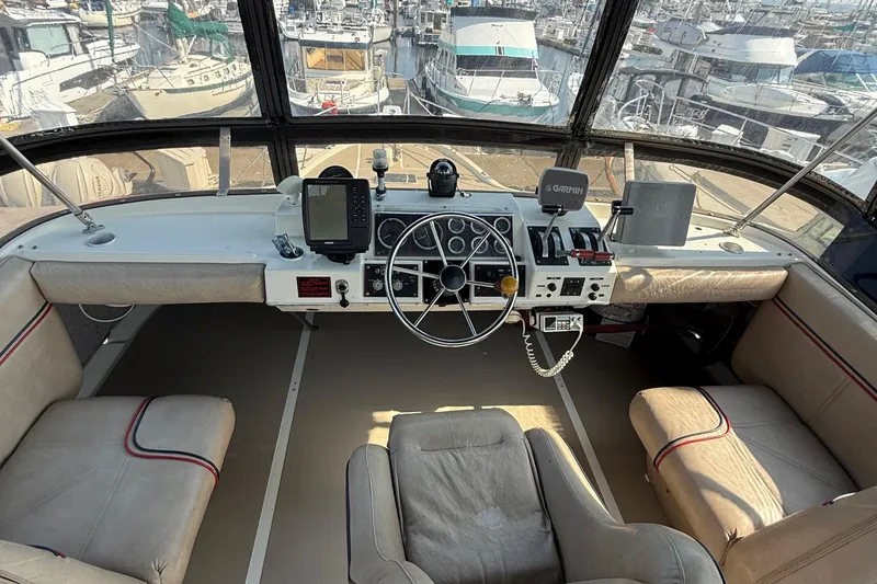 Slide: The Image of 1983 Bayliner 3870 Motoryacht helm with steering wheel, navigation equipment, and marina view. - 6