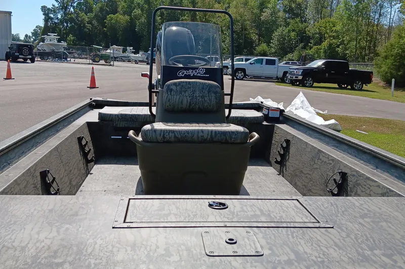 Slide: The Image of 2026 Tracker Grizzly 1860 CC boat interior with seating, parked outdoors. - 7