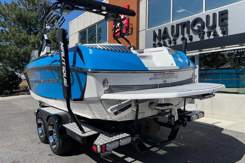 Slide: The Image of 2016 Nautique Super Air Nautique G21 boat in blue and white, parked outside dealership. - 3