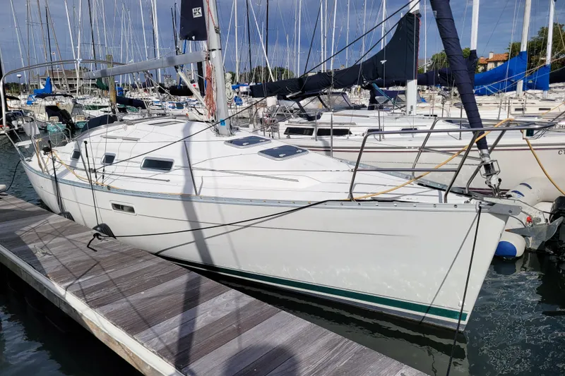 Slide: The Image of 2002 Beneteau Oceanis 311 sailboat docked in a marina, surrounded by other vessels. - 0