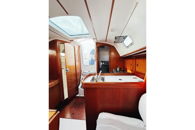 Slide: The Image of Interior of 2002 Beneteau Oceanis 311 sailboat, featuring wooden cabinetry and compact kitchen area. - 18