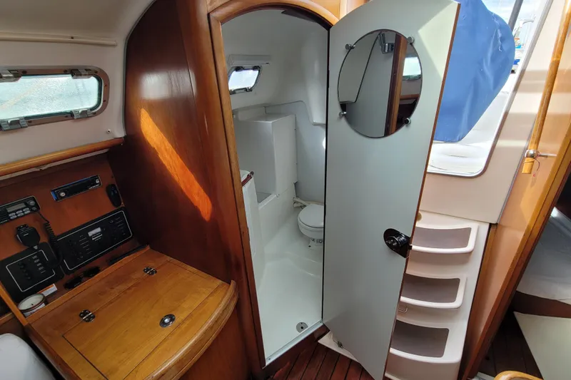 Slide: The Image of Interior of 2002 Beneteau Oceanis 311 sailboat, featuring a compact bathroom and navigation station. - 21