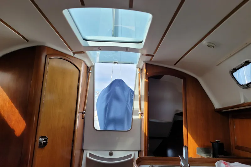 Slide: The Image of Interior view of 2002 Beneteau Oceanis 311 sailboat with wooden cabinetry and skylight. - 25