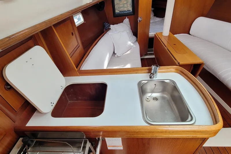 Slide: The Image of Interior of 2002 Beneteau Oceanis 311 sailboat with compact kitchen and seating area. - 28