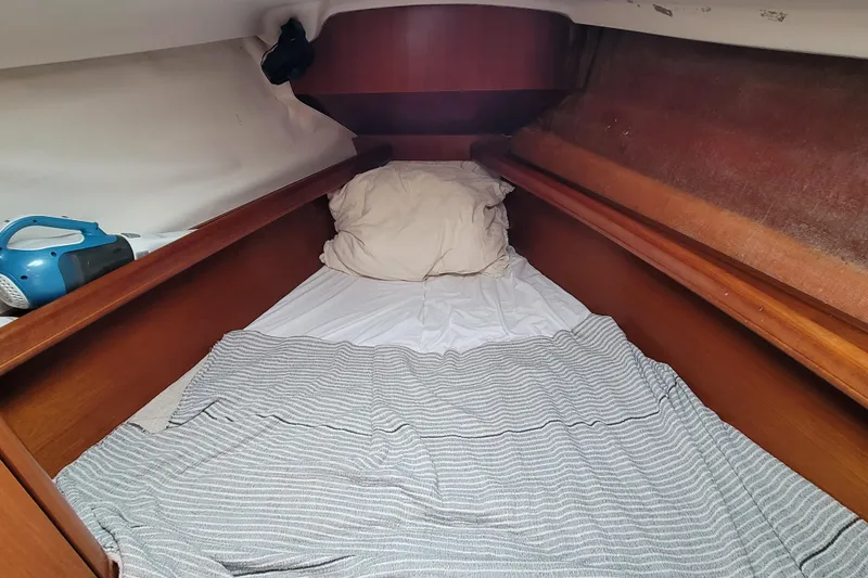 Slide: The Image of Cozy cabin interior of 2002 Beneteau Oceanis 311 sailboat with bed and striped blanket. - 33