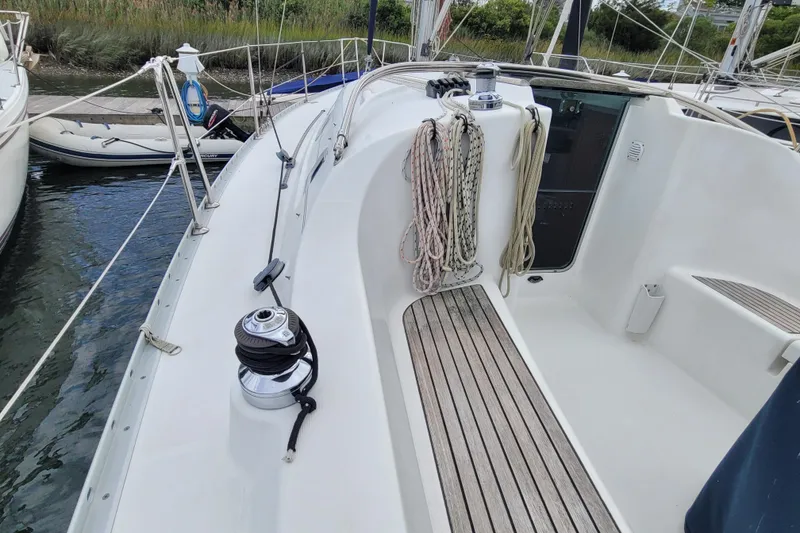 Slide: The Image of 2002 Beneteau Oceanis 311 sailboat deck with winch and ropes, docked by the water. - 5