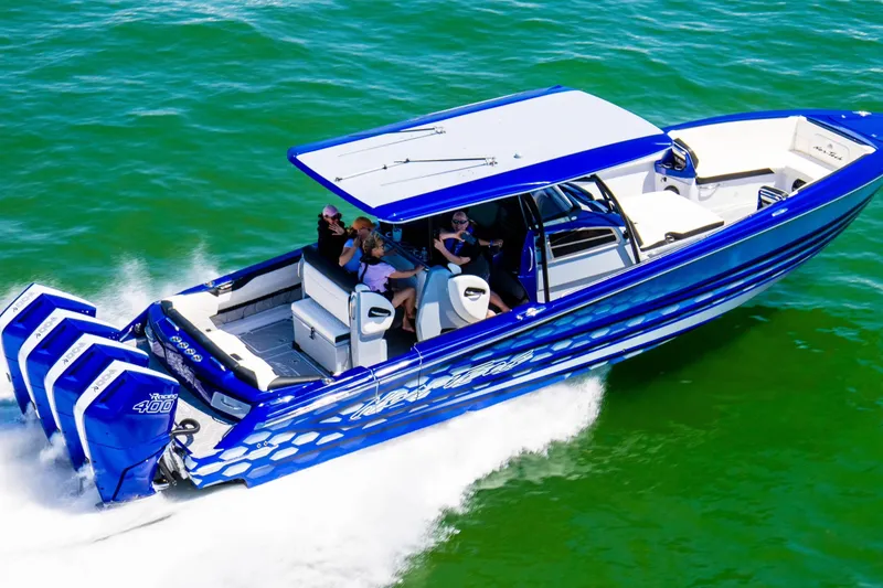 The Image of 2025 Nor-Tech 390 Sport boat cruising on vibrant green water, featuring triple outboard engines. - 0