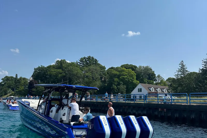 Slide: The Image of 2025 Nor-Tech 390 Sport boat docked near a scenic waterfront with trees and a house. - 14