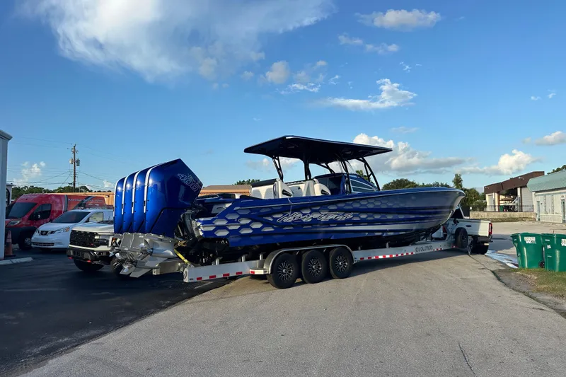 Slide: The Image of 2025 Nor-Tech 390 Sport boat on trailer, blue design, parked outdoors. - 6