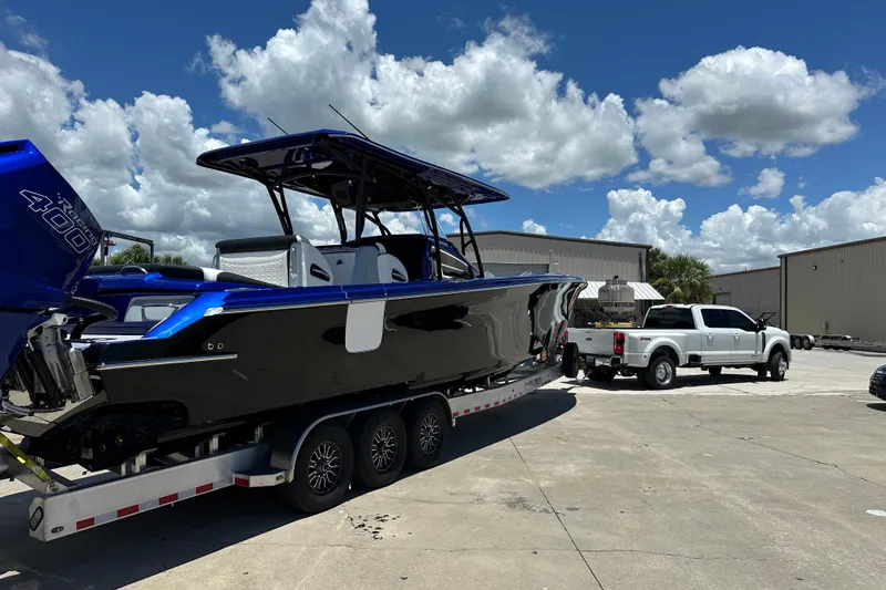 Slide: The Image of 2025 Nor-Tech 390 Sport boat on trailer, parked beside a white truck under a blue sky. - 16