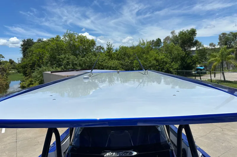 Slide: The Image of 2025 Nor-Tech 390 Sport boat roof against a clear blue sky and lush greenery. - 20