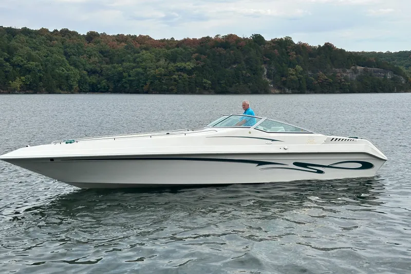 Slide: The Image of 1999 Envision 3200 Intruder boat on a lake with forested shoreline. - 0