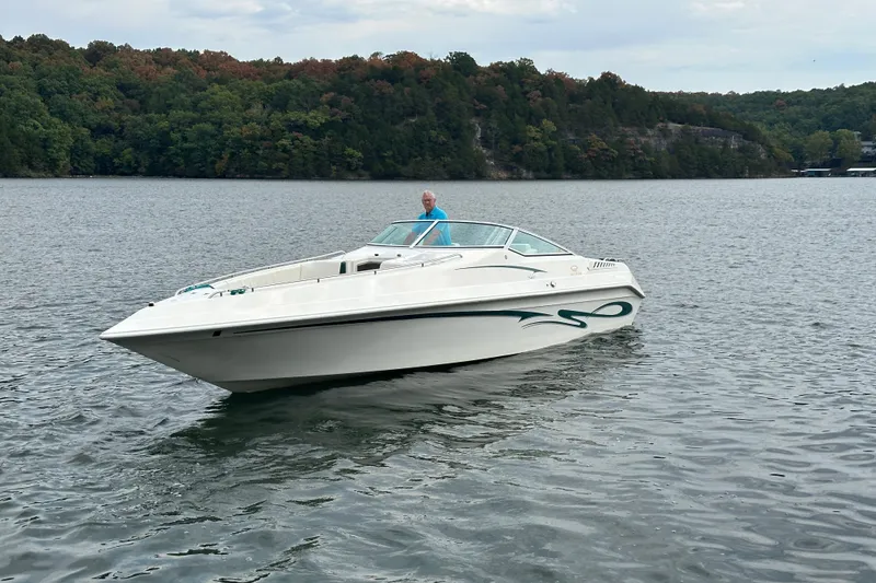 Slide: The Image of 1999 Envision 3200 Intruder boat on a lake with forested shoreline. - 1