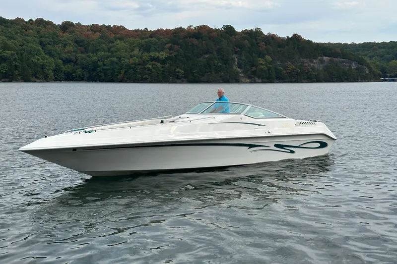 Slide: The Image of 1999 Envision 3200 Intruder boat on a lake with forested shoreline. - 2