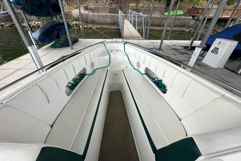 Slide: The Image of Interior view of a 1999 Envision 3200 Intruder boat docked, featuring white seating and teal accents. - 22