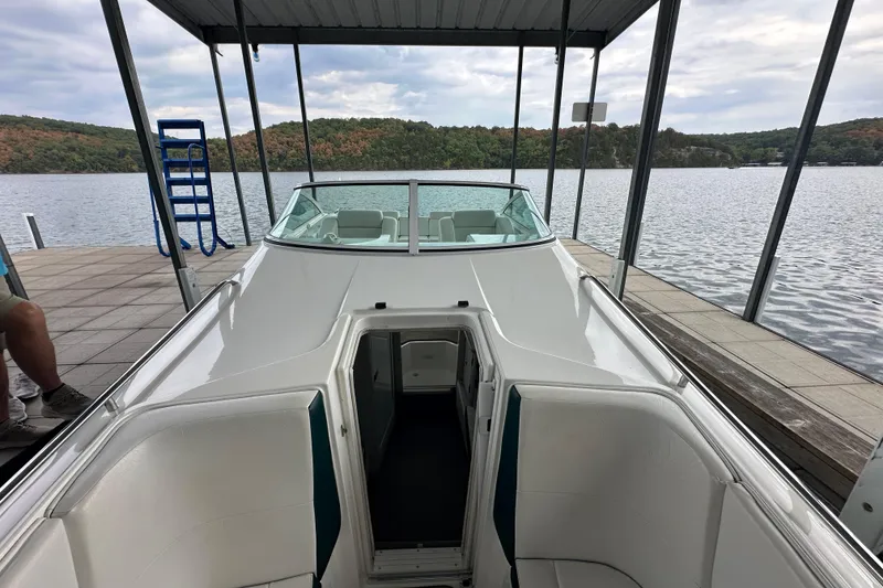 Slide: The Image of 1999 Envision 3200 Intruder boat docked on a scenic lake under a covered pier. - 24