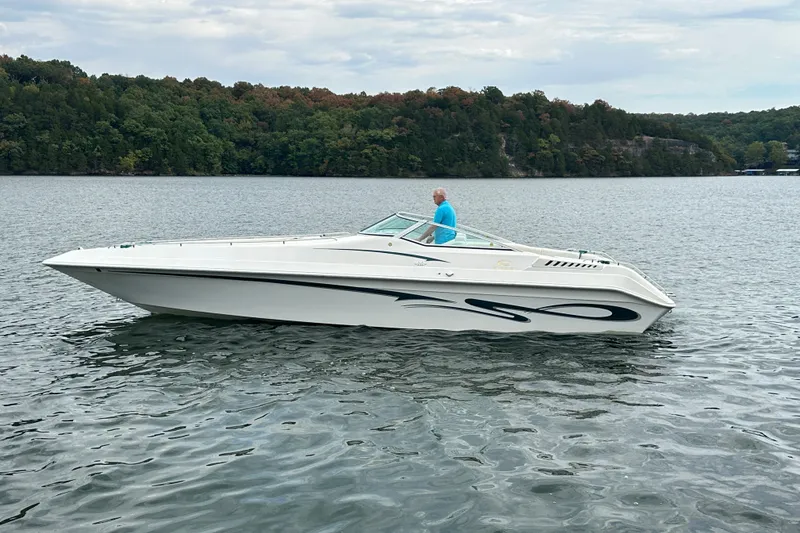 Slide: The Image of 1999 Envision 3200 Intruder boat on a lake with forested shoreline. - 3