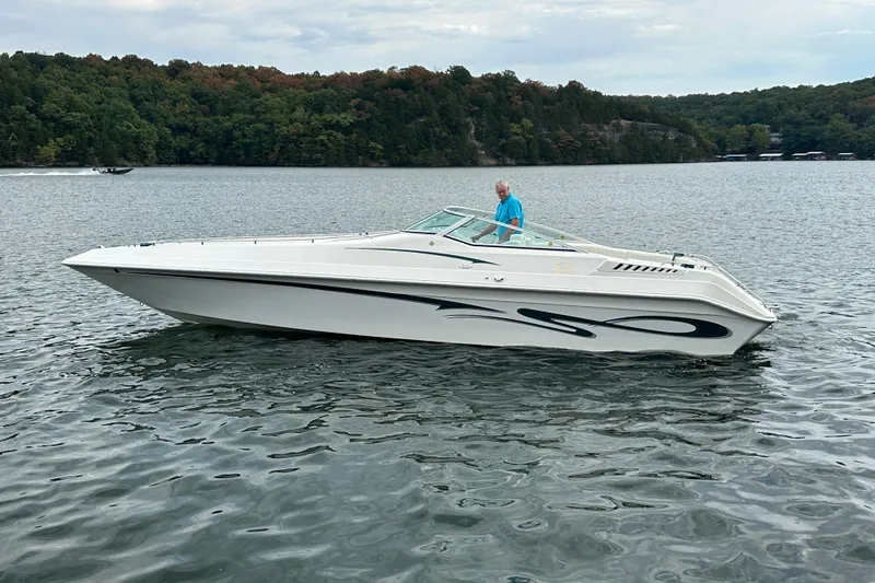 Slide: The Image of 1999 Envision 3200 Intruder boat on a calm lake with forested shoreline. - 4