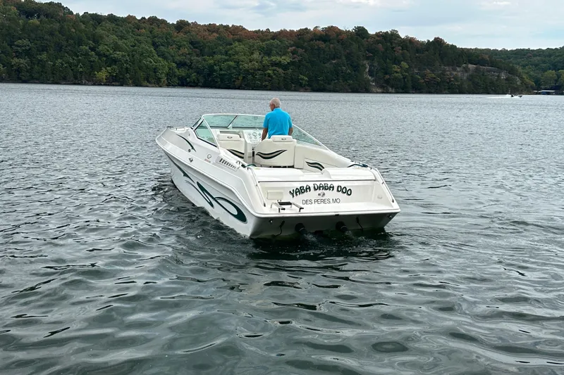 Slide: The Image of 1999 Envision 3200 Intruder boat on a lake, surrounded by lush green trees. - 6