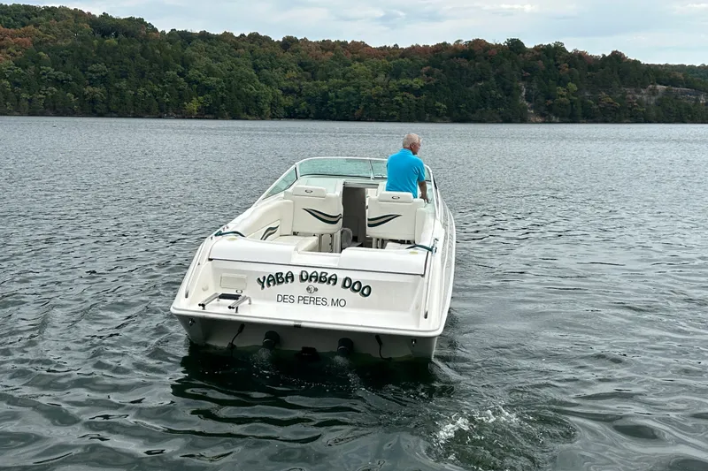 Slide: The Image of 1999 Envision 3200 Intruder boat on a lake, with lush green forest backdrop. - 8