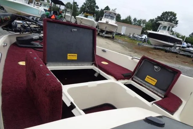 Slide: The Image of 1996 Quantum 180 XD boat with open storage compartments, red interior, and surrounding boats. - 8