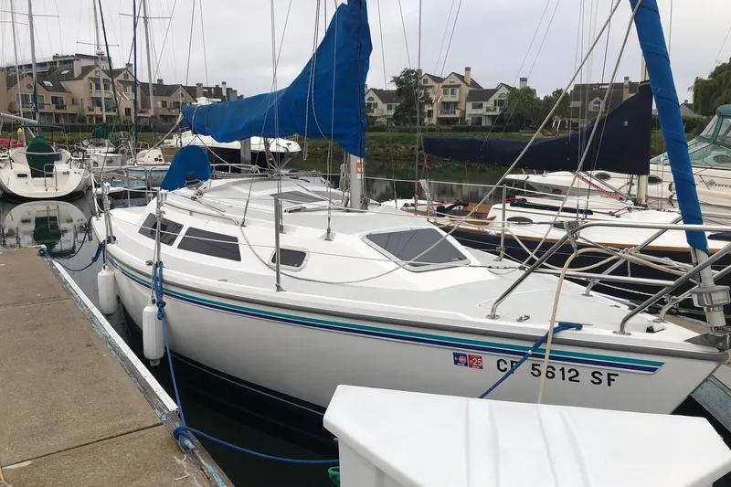 Slide: The Image of 1995 Catalina 270 sailboat docked in a marina with residential buildings in the background. - 2