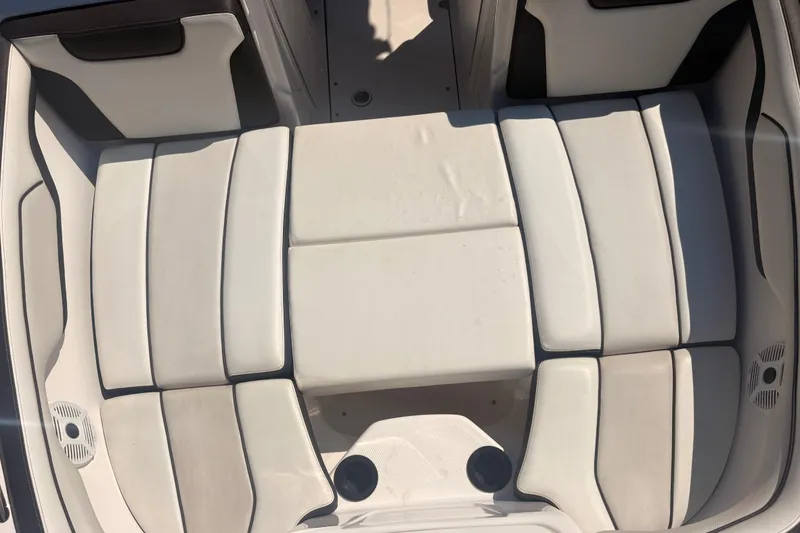 Slide: The Image of 2018 Yamaha Boats SX210 interior seating, featuring white cushioned seats and cup holders. - 16