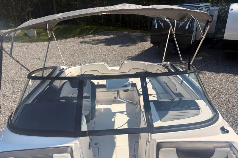 Slide: The Image of 2018 Yamaha Boats SX210 with canopy, parked on gravel, showcasing interior seating. - 17