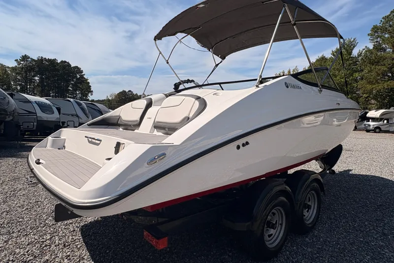 Slide: The Image of 2018 Yamaha Boats SX210 on trailer, parked outdoors with RVs in background. - 2