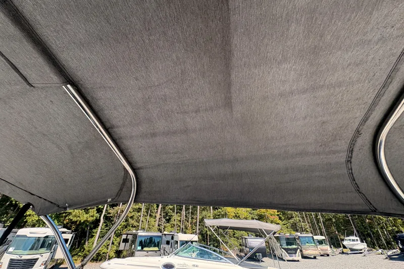 Slide: The Image of 2018 Yamaha Boats SX210 with canopy, parked among other boats and RVs. - 27